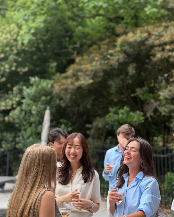 Guests laughing together with glasses of white wine on a shaded patio